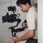 Videomaker utiliza um estabilizador para filmar em um ambiente interno.