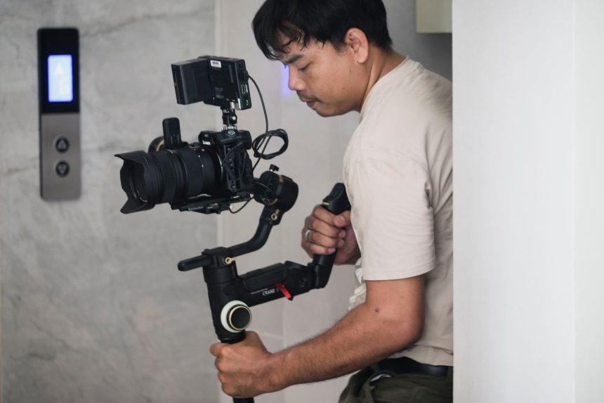 Videomaker utiliza um estabilizador para filmar em um ambiente interno.
