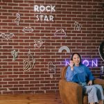 Criadora de conteúdo realiza uma transmissão ao vivo em um ambiente com iluminação neon e decoração moderna.